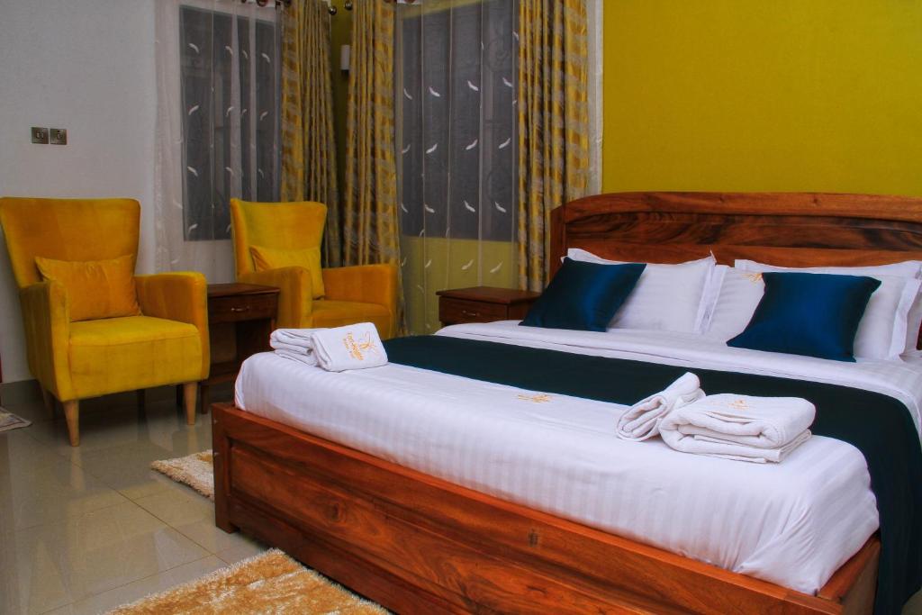 a bedroom with two beds and a chair at Fort Heights Homestay in Fort Portal