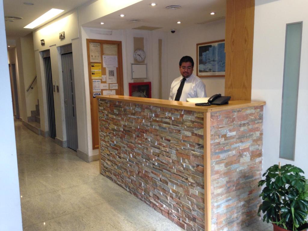 a man standing at a counter in a lobby at Blanro Hotel in Buenos Aires