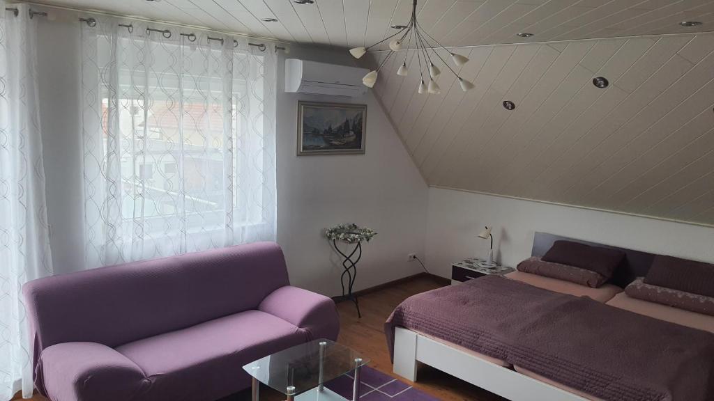 sala de estar con sofá púrpura y cama en Nettes 2- Zimmer Apartment, en Sehnde
