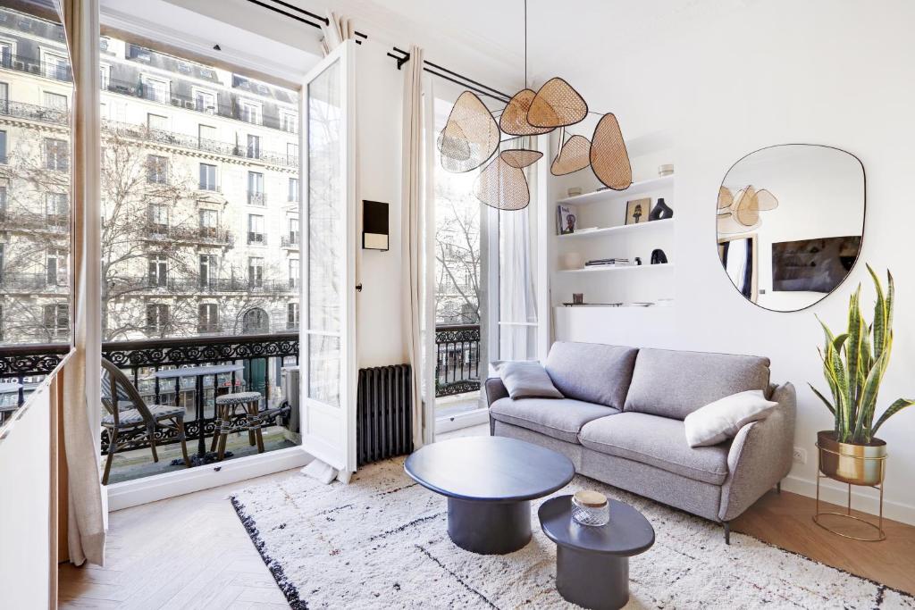 un salon avec un canapé et une grande fenêtre dans l'établissement Pick A Flat's Apartments in Opéra - Rue de Richelieu, à Paris
