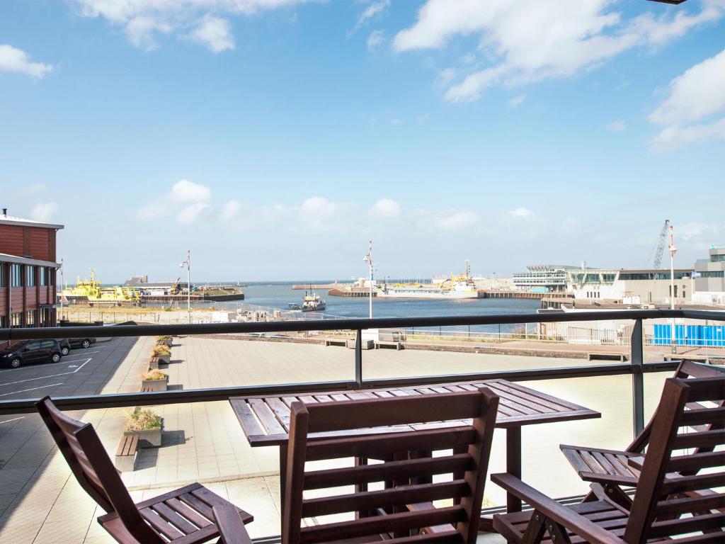 a balcony with chairs and a table and a view of the ocean at Apartment overlooking the Scheveningen harbor in Scheveningen