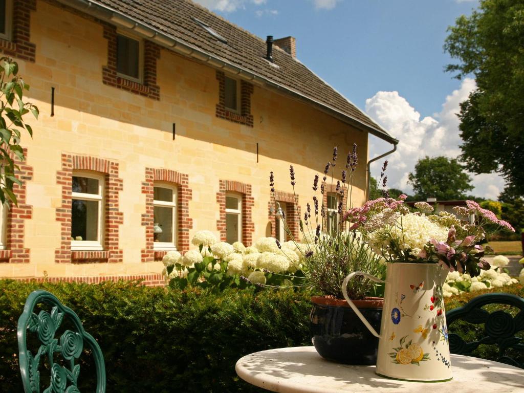 a table with a vase of flowers and a building at Bright Farmhouse in Gulpen Netherlands With Garden in Stokhem