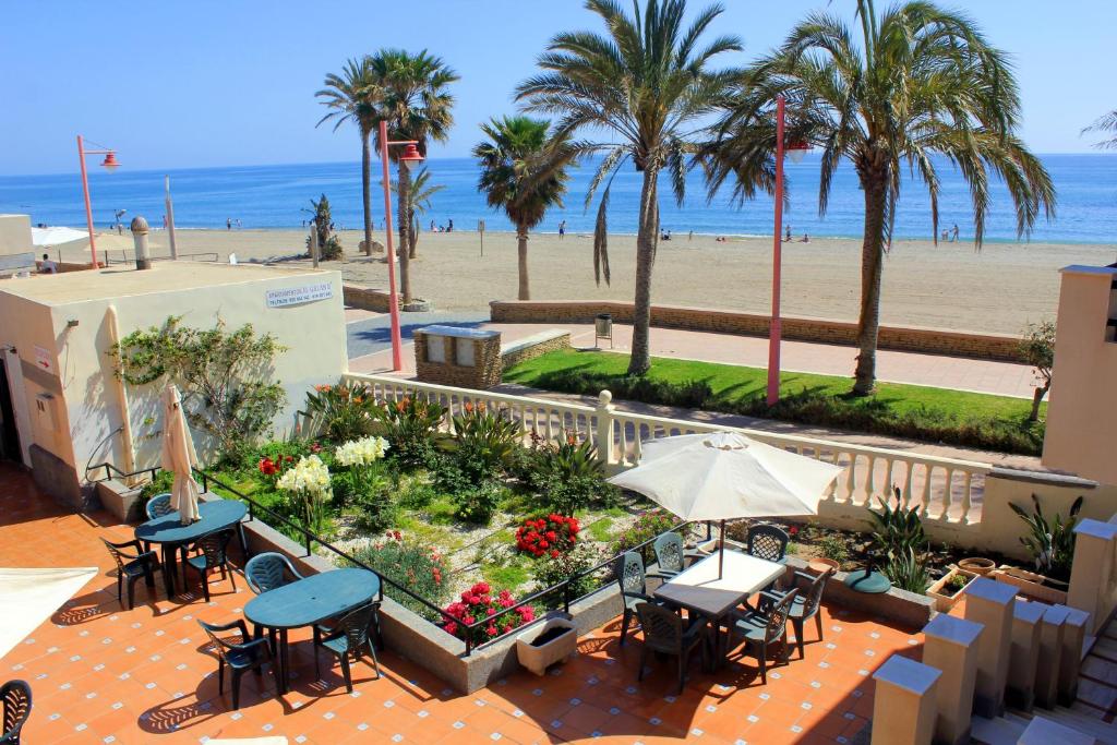 een terras met tafels en stoelen en een strand bij Apartamentos El Galán II in Carboneras