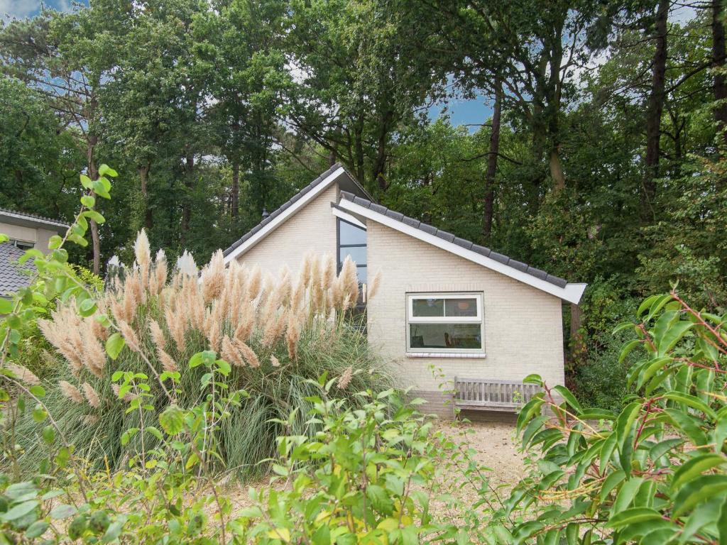 una pequeña casa blanca con un banco delante en Elite Holiday Home in North Holland near Forest, en Schoorl