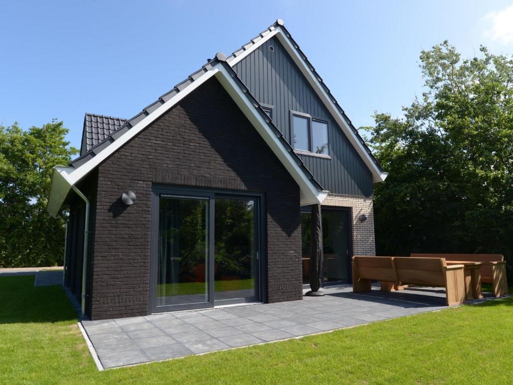a brick house with a bench in the yard at Beautiful villa, Den Burg Texel in Westermient