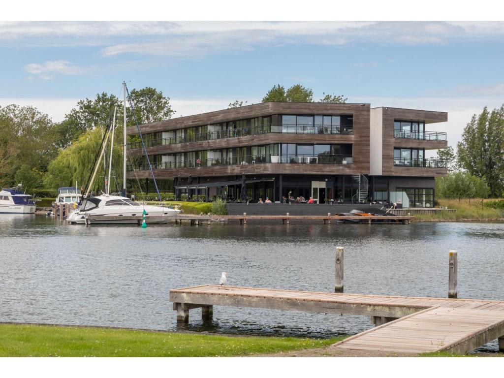 a building on the water with a dock and a boat at Holiday apartment in a prime location on the Veerse lake in Arnemuiden