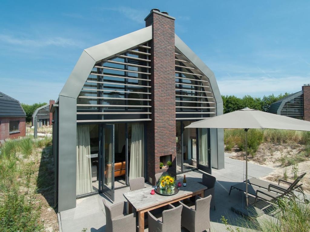 エグモント・アーン・デン・フフにあるHoliday home in Egmond aan den Hoef with saunaの傘とテーブルのある建物