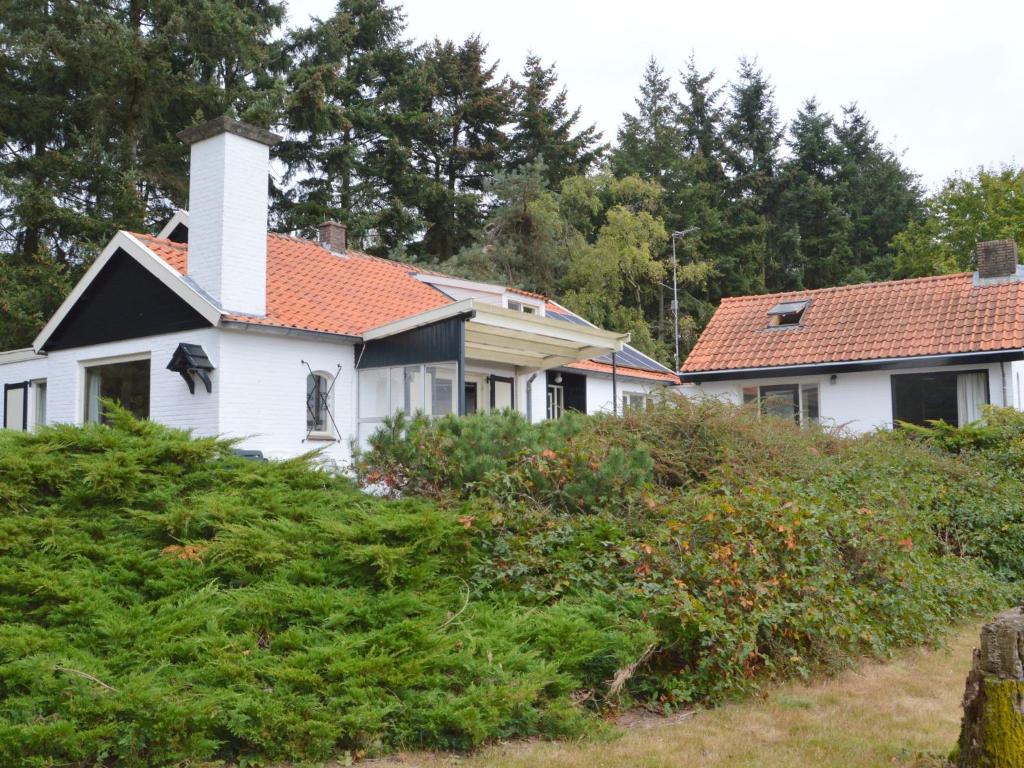 una casa blanca con una chimenea en la parte superior de algunos arbustos en Quaint Mansion in Oploo with Terrace en Oploo