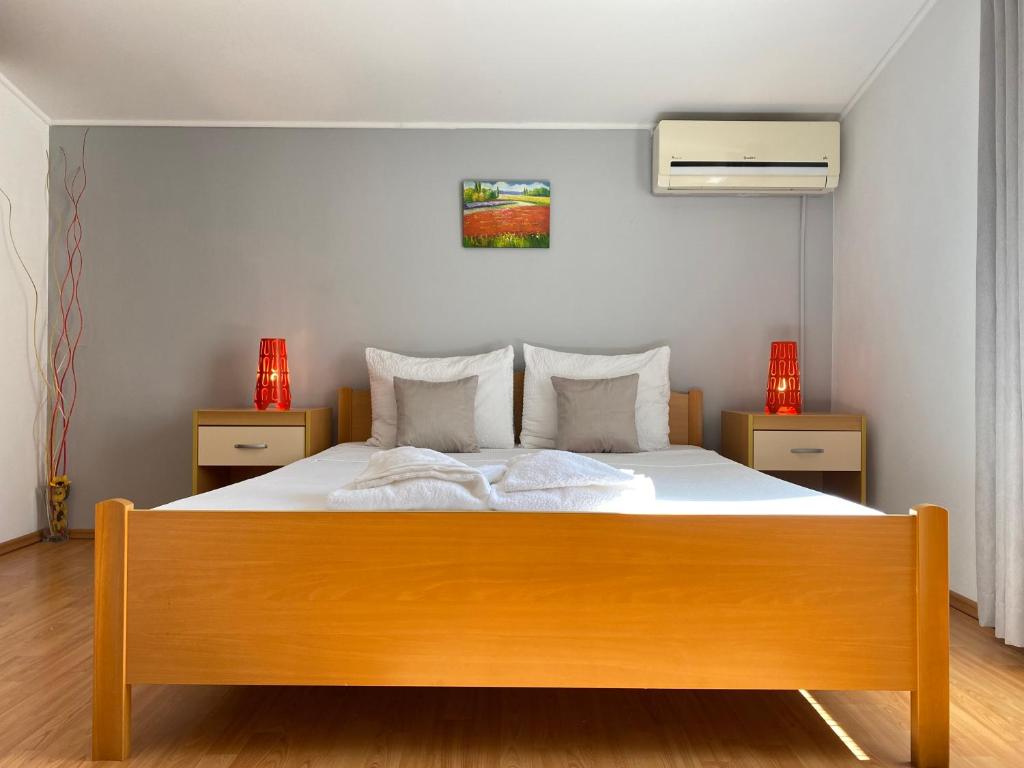 een slaapkamer met een houten bed met witte lakens en kussens bij Apartments Gajić in Fažana