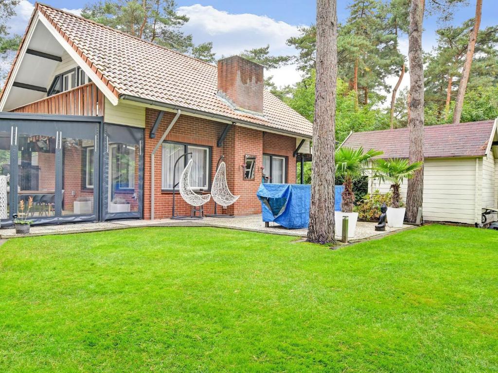 uma casa com um relvado e duas cadeiras no quintal em Charming holiday home with a covered terrace em Meijel