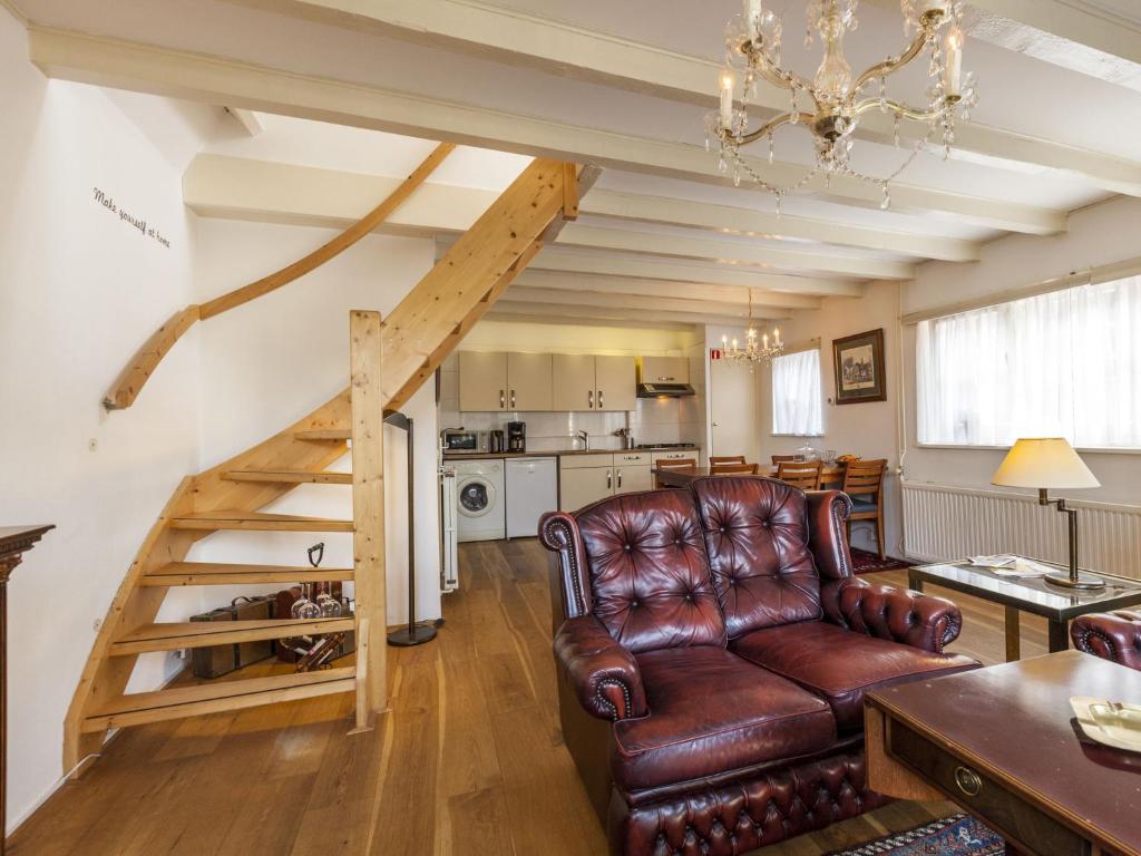 a living room with a brown leather couch and a staircase at Sunny holiday home near the sea in Wemeldinge