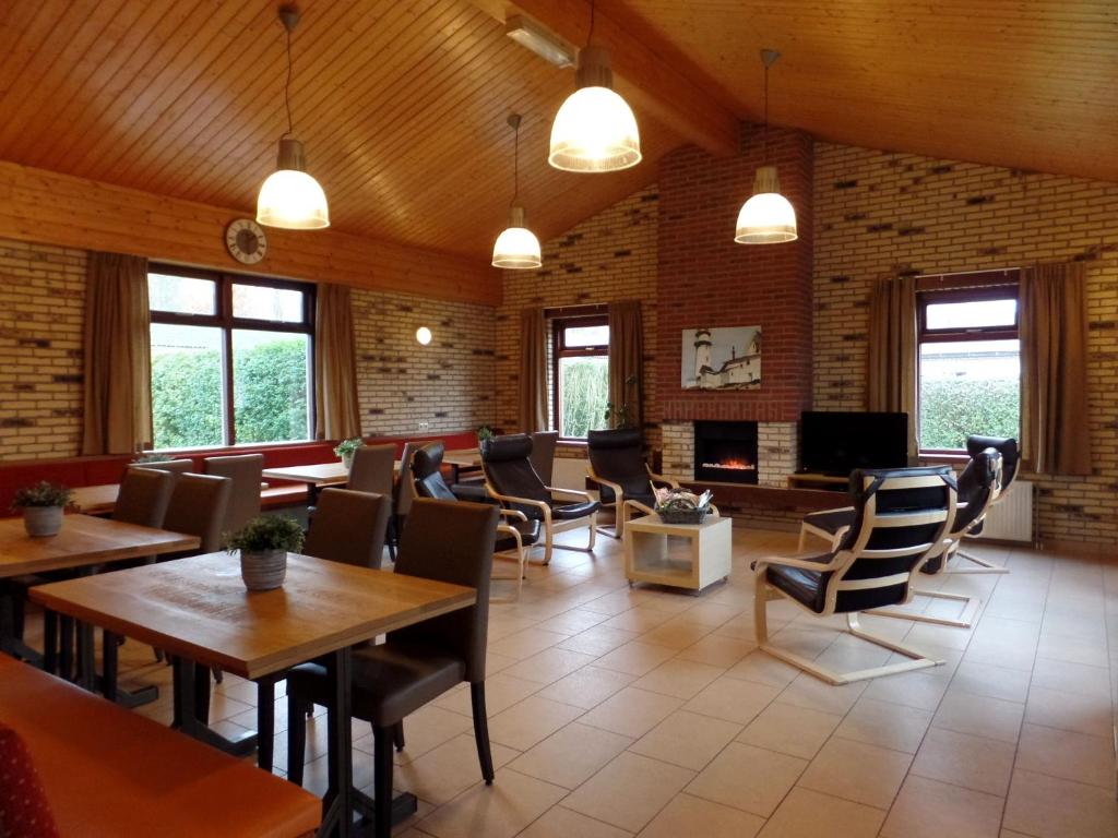een restaurant met tafels en stoelen en een open haard bij Detached house with private pool 1km walk to the sandy beach in Ellemeet
