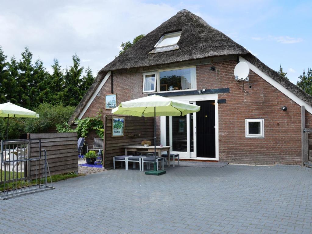 een huis met een rieten dak, een tafel en een paraplu bij Beautiful farmhouse in Wapse with fenced garden in Wapse