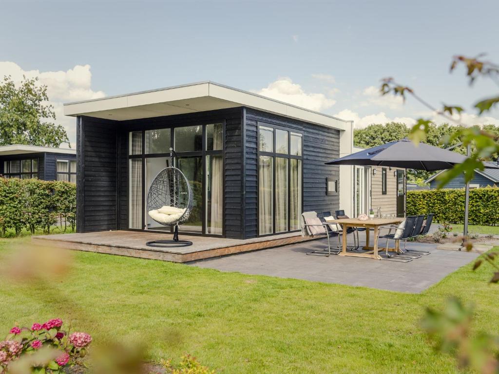 een zwart tiny house met een tafel en een paraplu bij Modern bungalow with nice garden at forest edge in Rijssen