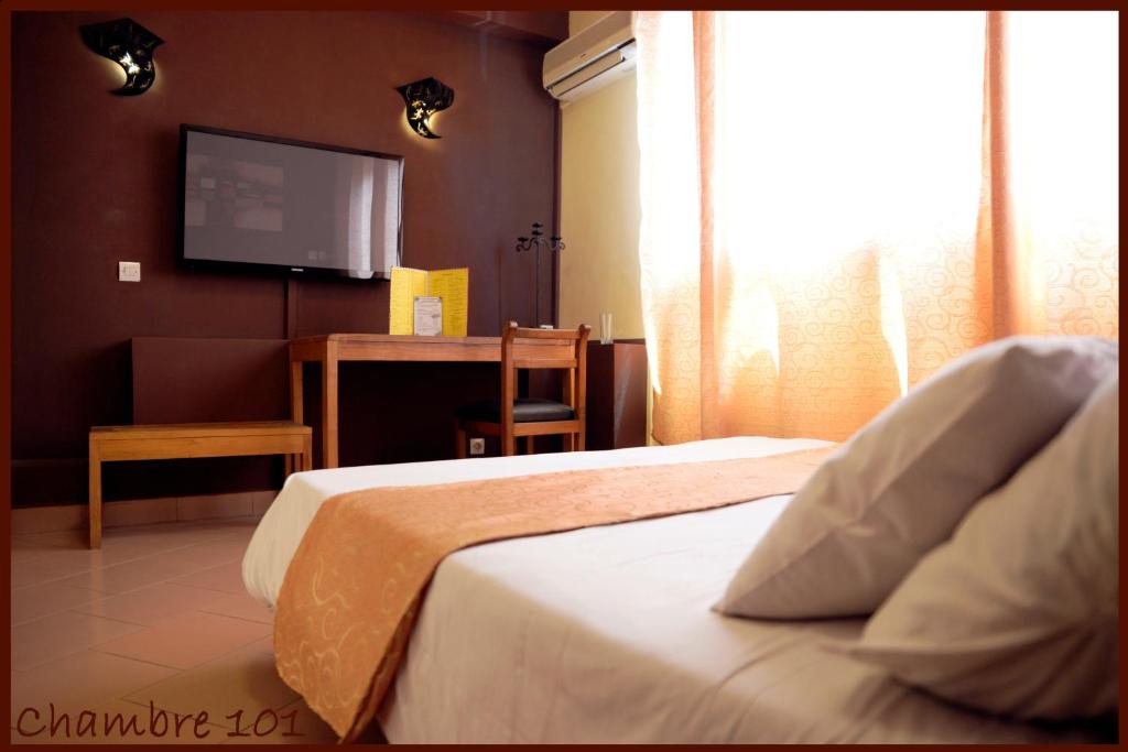 Habitación de hotel con 2 camas y TV de pantalla plana. en Hotel Le Relais Normand en Antananarivo