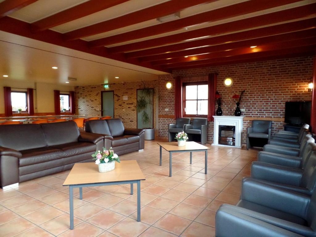 een woonkamer met banken en tafels en een open haard bij Stone house with private pool and garden in quiet place in Ellemeet