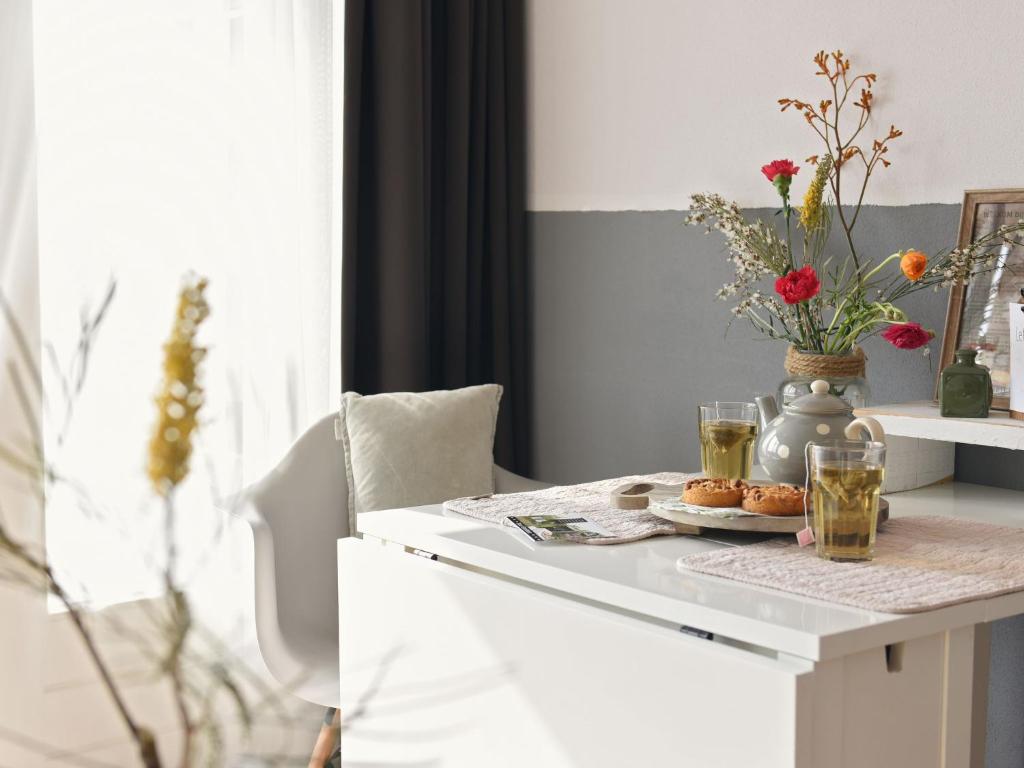 uma mesa com dois copos e um vaso com flores em Modern suites near beach em Callantsoog