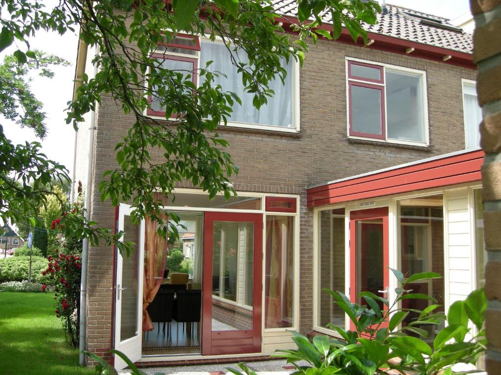 una casa con porte scorrevoli in vetro rosse e bianche di Tranquil holiday home in West Gradijk a West-Graftdijk