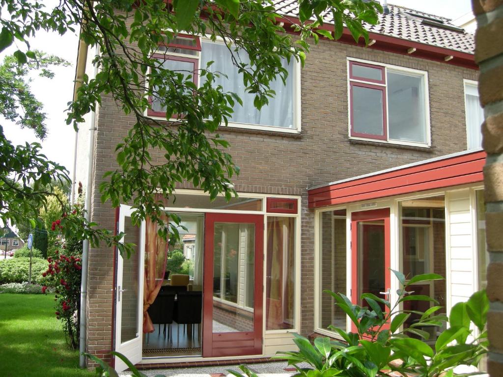 une maison avec des portes coulissantes en verre rouge et blanc dans l'établissement Tranquil holiday home in West Gradijk, à West-Graftdijk