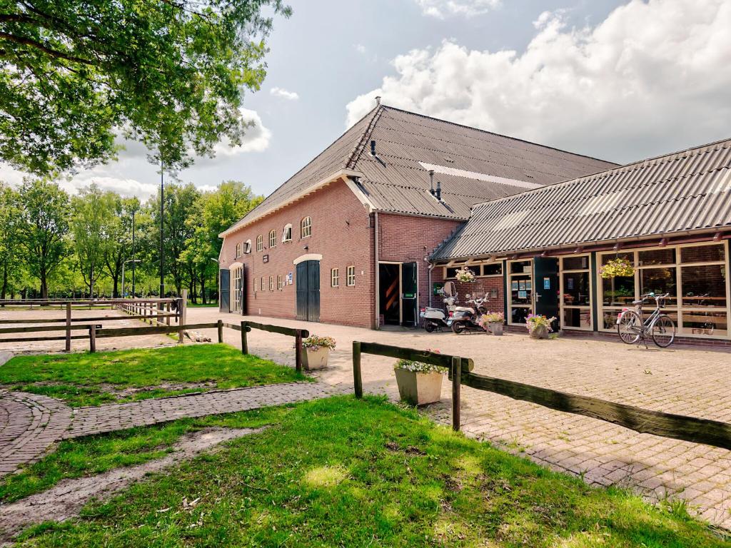 een rood bakstenen gebouw met een hek ervoor bij Restful Holiday Home with a Private Terrace and hottub in Veendam