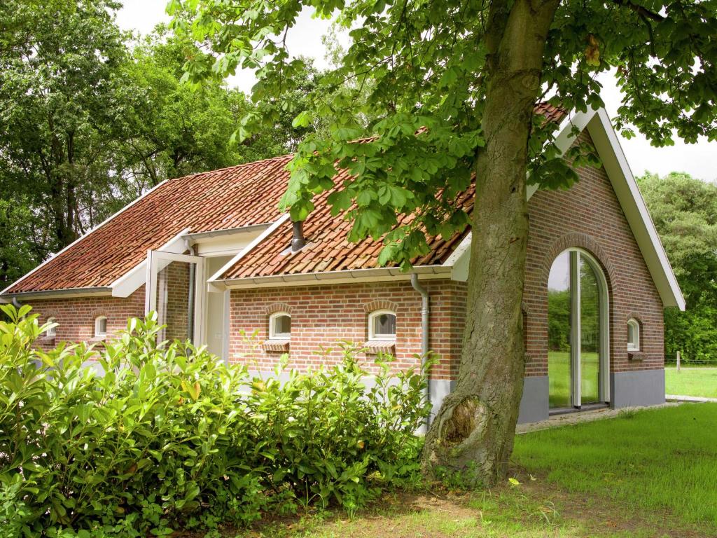 ハークスベルヘンにあるLovely Design Countryside Holiday Homeの庭に木のある小さなレンガ造りの家
