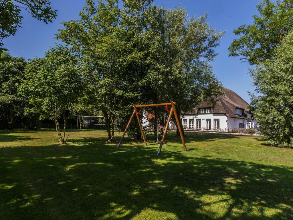 a swing set in a yard with a house at Great Farmhouse in De Cocksdorp with Garden in De Cocksdorp