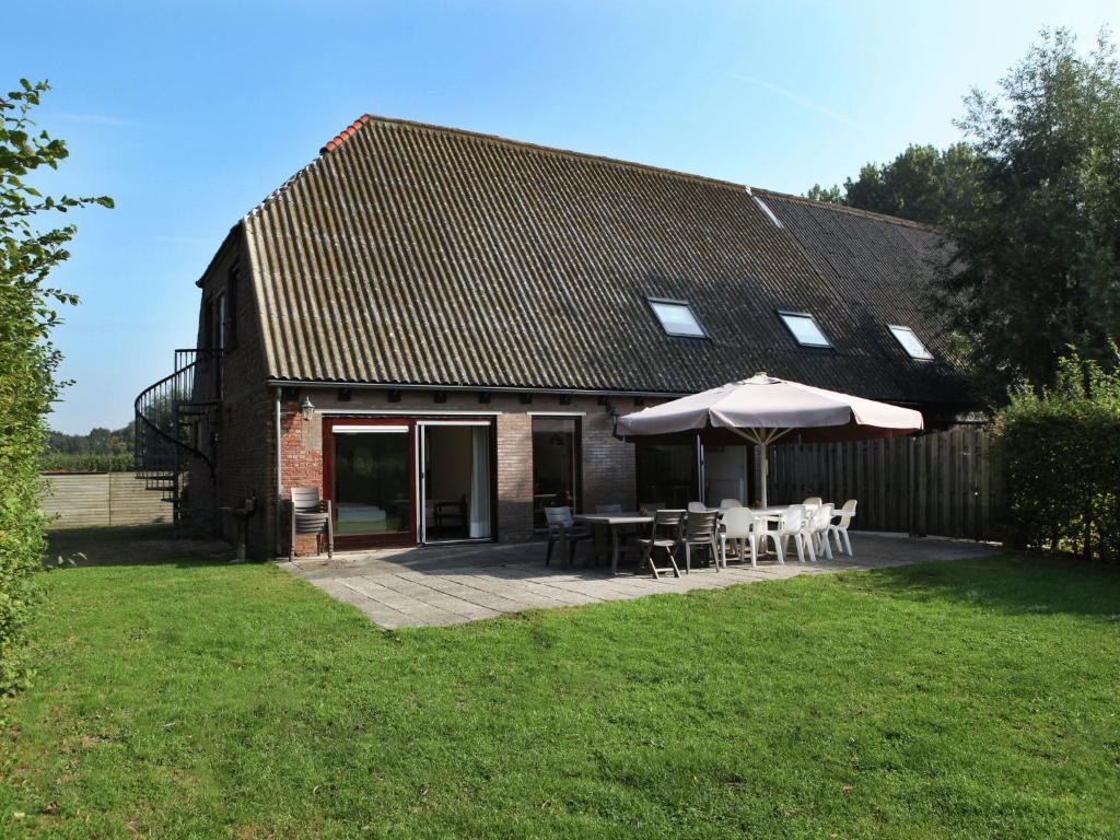 a house with an umbrella and tables and chairs at Farmhouse home in Eede in Eede