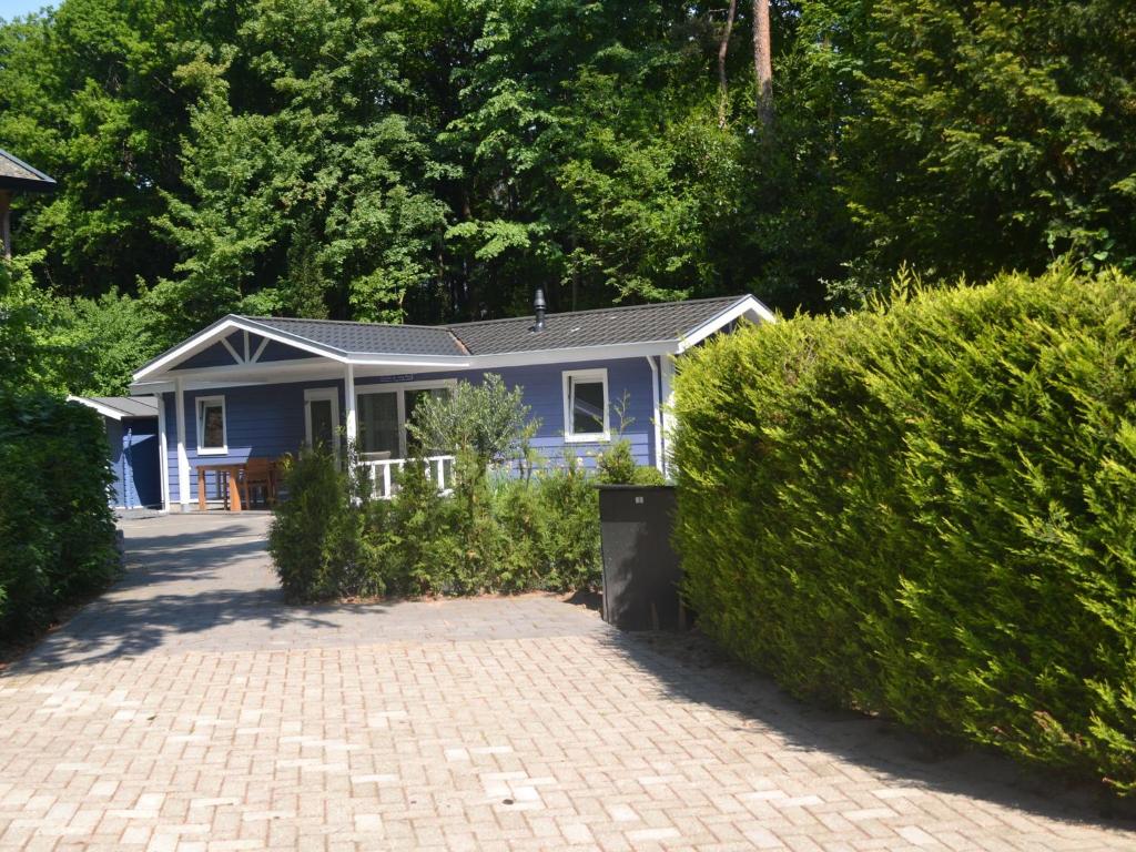 een blauw huis midden in een tuin bij Lovely chalet with covered terrace in a holiday park on the edge of the forest in Rhenen