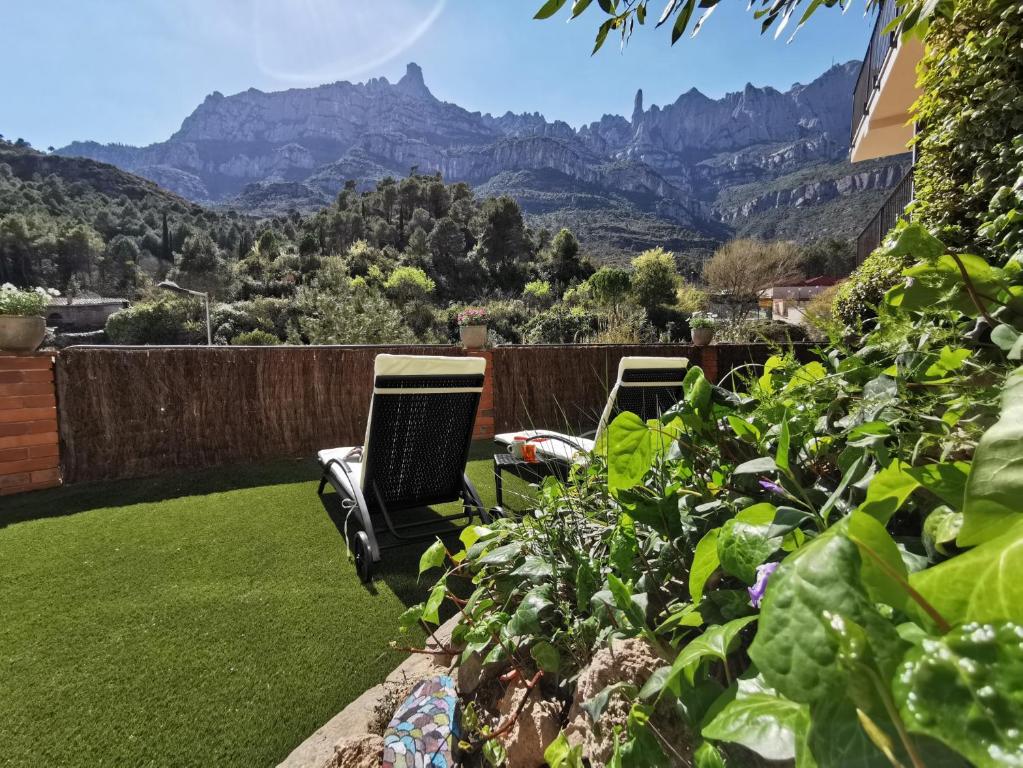 two chairs on a lawn with mountains in the background at Apartaments Agulles de Montserrat in Monistrol