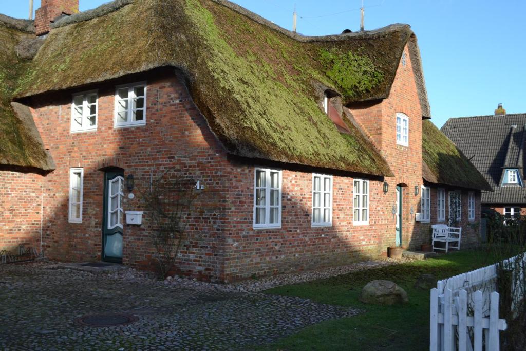 an old brick building with a grass roof at Ferienhaushälfte am Museum in Alkersum