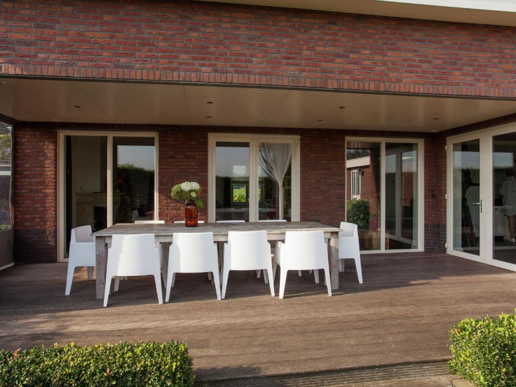 een tafel en witte stoelen op een patio bij Luxurious holiday home with wellness, in the middle of the North Brabant nature reserve near Leende in Leende