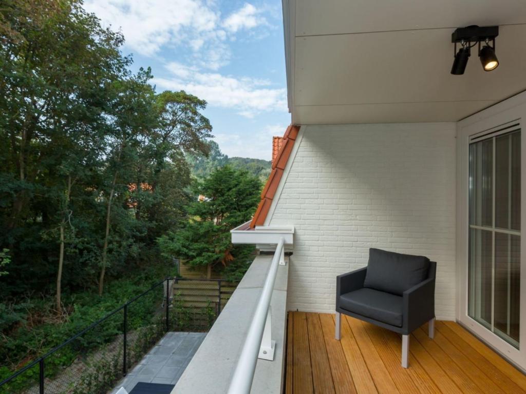 a chair sitting on the balcony of a house at Luxury apartment for 6 people with roof terrace and view of the dunes in Koudekerke