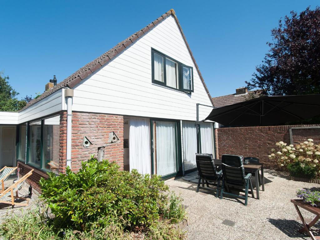 a house with a patio with chairs and a table at Attractive holiday home in Noordwijkerhout with garden in Noordwijkerhout