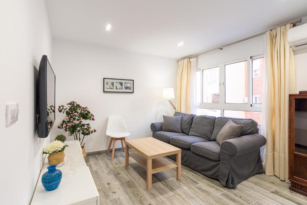 ein Wohnzimmer mit einem Sofa und einem Tisch in der Unterkunft Faro, bonito apartamento en la Malagueta in Málaga