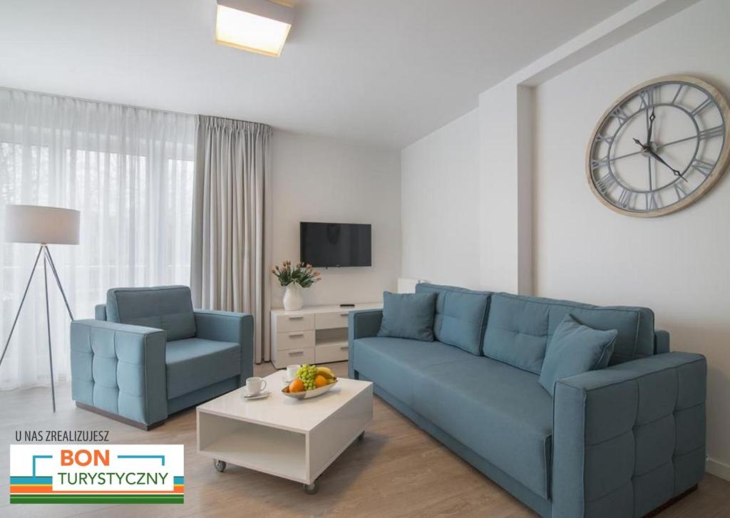 sala de estar con sofá azul y reloj en Apartament 65 Przy plazy en Władysławowo
