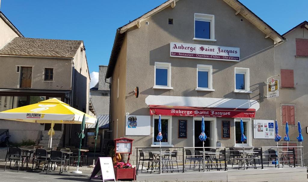 un restaurant avec des tables et des chaises en face d'un bâtiment dans l'établissement Auberge Saint Jacques, à Saint-Alban-sur-Limagnole