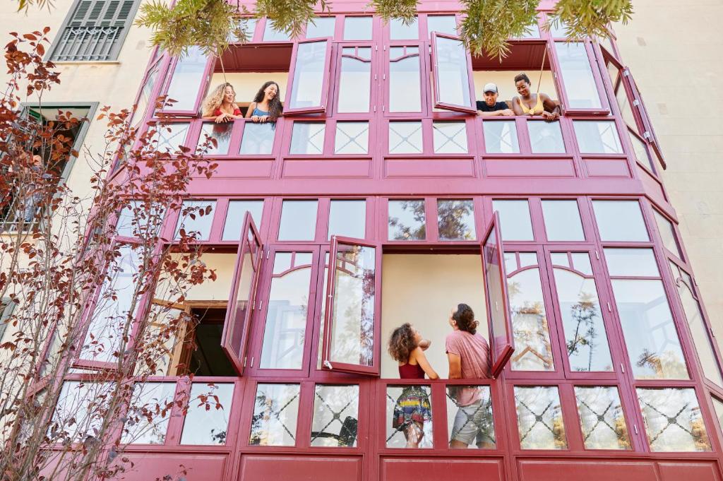 a group of people looking out of a pink building at The Boc Hostels - Palma in Palma de Mallorca