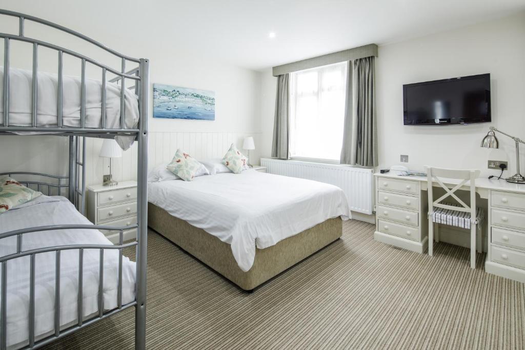 a bedroom with two bunk beds and a desk and a television at Ommaroo Hotel in Saint Helier Jersey