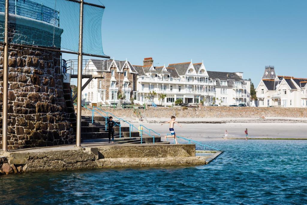 Una mujer caminando por las escaleras hacia la playa en Ommaroo Hotel en Saint Helier