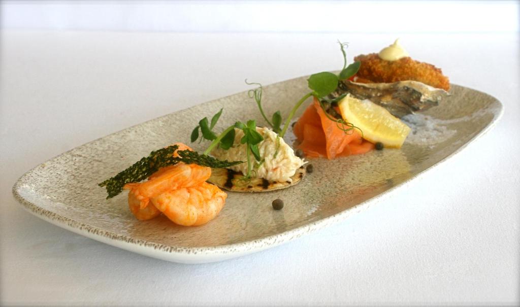 a plate of food with shrimp and vegetables on it at Ommaroo Hotel in Saint Helier Jersey