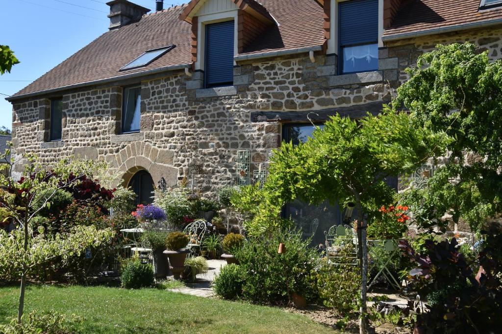 une maison en pierre avec un jardin en face dans l'établissement La Grange Bagnolaise, à Bagnoles-de-l'Orne