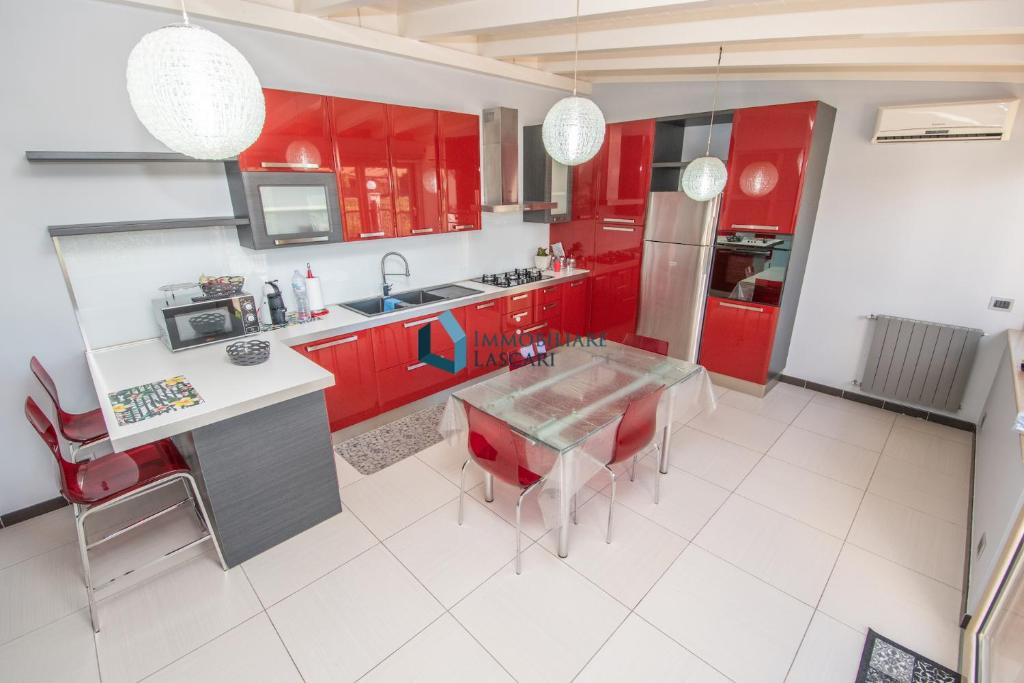 een keuken met rode kasten en een tafel en stoelen bij Red Luxury a pochi passi dal mare in Campofelice di Roccella