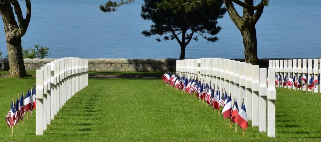 a white fence with american flags in the grass at Villa kahlo Omaha Beach in Colleville-sur-Mer