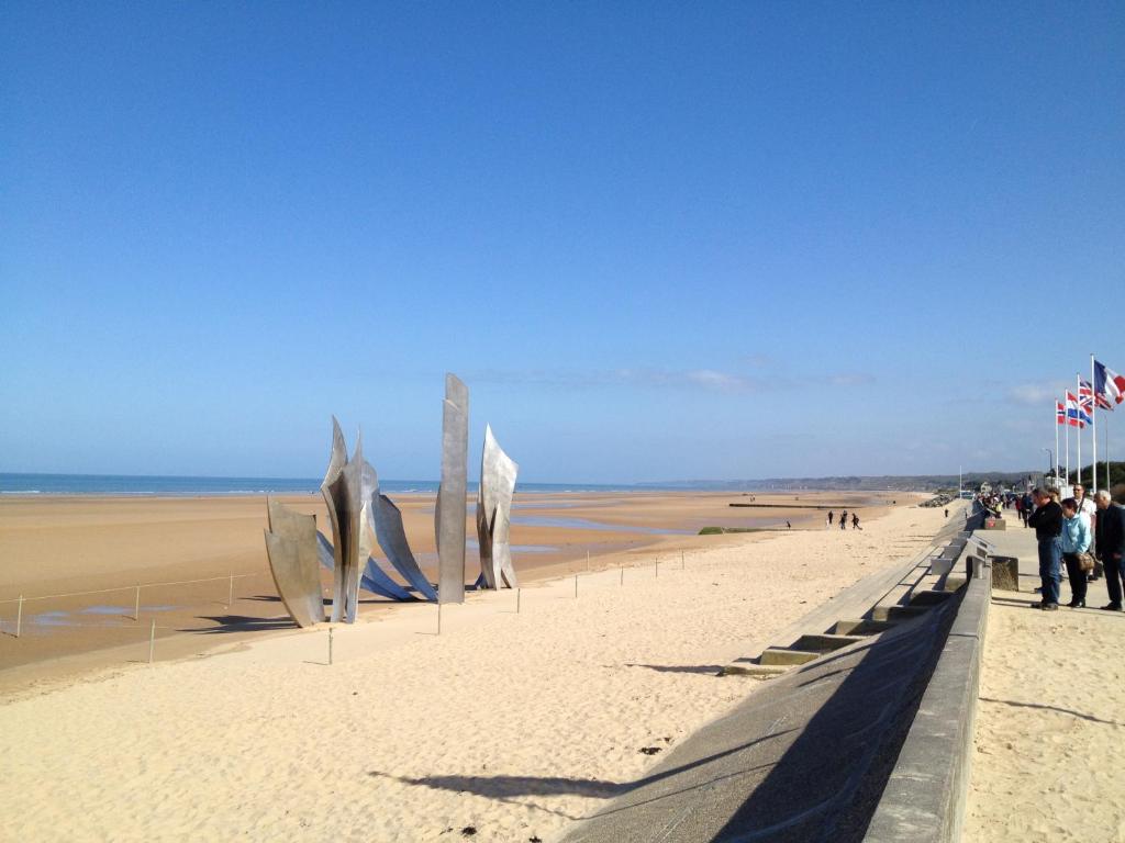 a sandy beach with flags and sculptures on it at Villa kahlo Omaha Beach in Colleville-sur-Mer