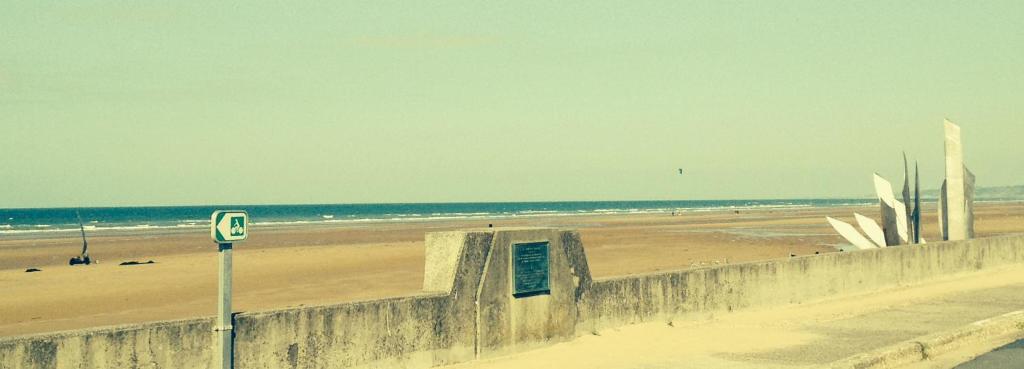 a beach with a retaining wall and a beach with the ocean at Villa kahlo Omaha Beach in Colleville-sur-Mer
