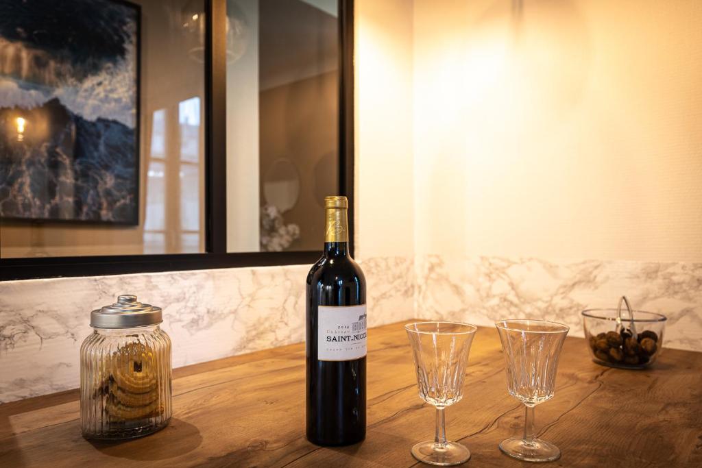 a bottle of wine sitting on a table with two glasses at Le LOUIS XV halte romantique à Metz centre in Metz