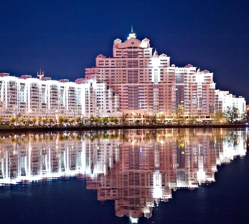 un gran edificio con su reflejo en el agua en Апартаменты Гостиный Дом, en Minsk