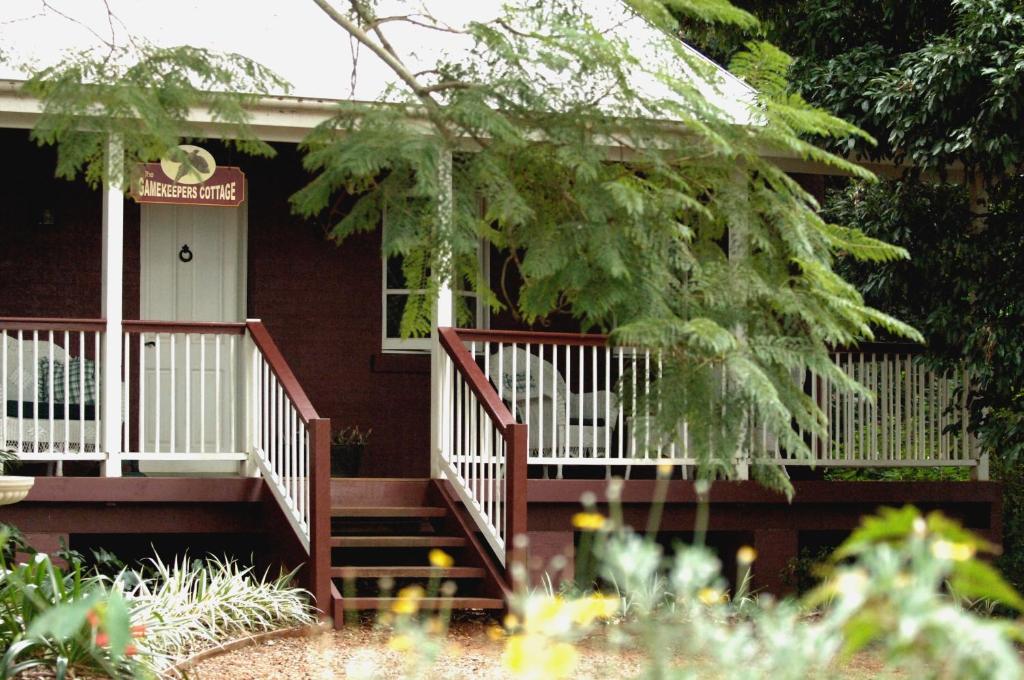 une petite maison avec une porte blanche et des escaliers. dans l'établissement Lisson Grove, à Mount Tamborine
