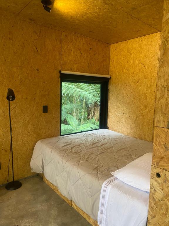 a bedroom with a bed and a window at Chalé dos Alpes in São Francisco de Paula