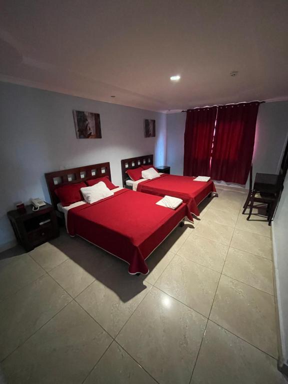 two beds in a bedroom with red sheets and pillows at Hospedaje Camino Real in Panama City